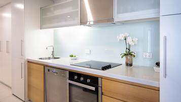 Una cocina moderna con electrodomésticos de acero inoxidable, lavavajillas y un lavamanos.