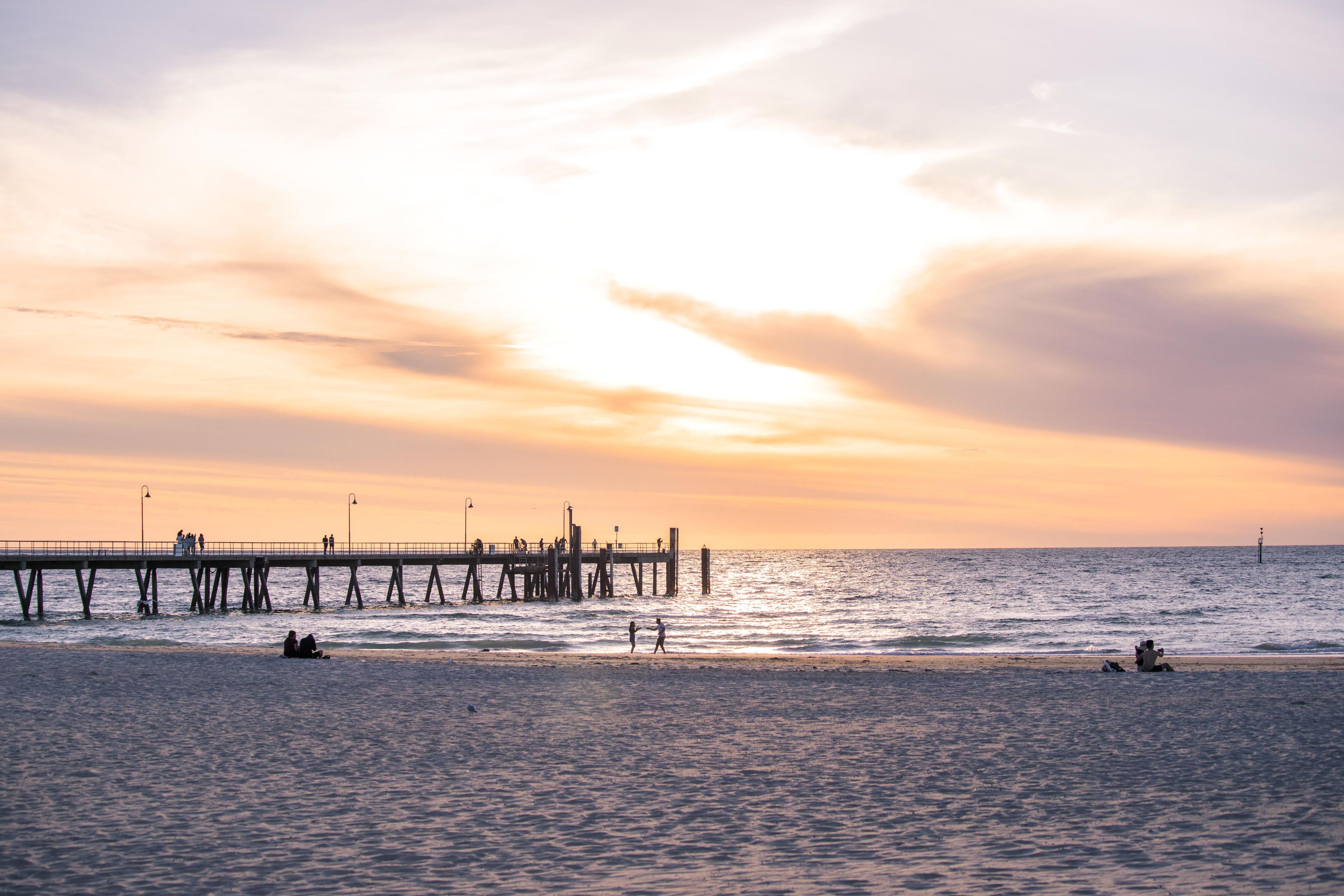A pier extending into calm waters with people walking along it.