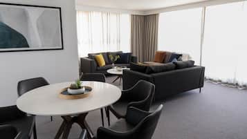 Una habitación de hotel moderna con un conjunto de sofás, una mesa de comedor y una planta pequeña sobre la mesa.