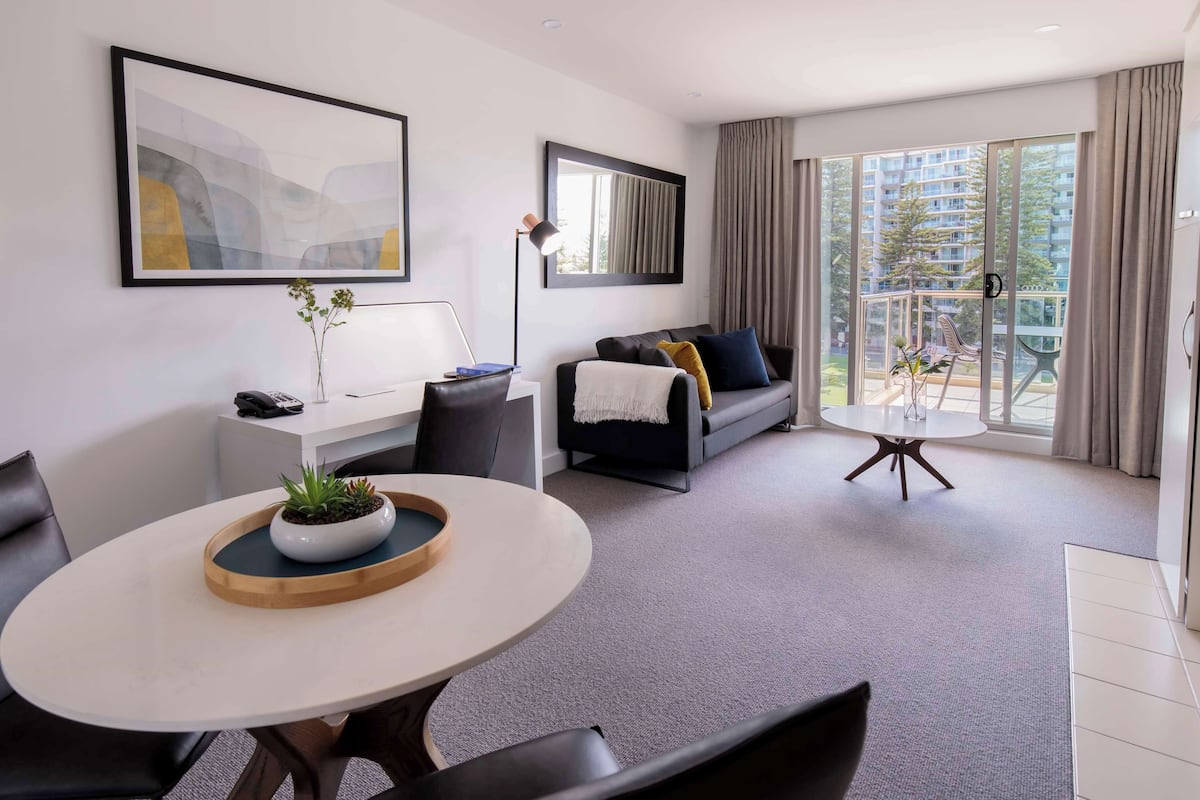 Een moderne woonkamer met een bank, een salontafel en een eethoek met stoelen.