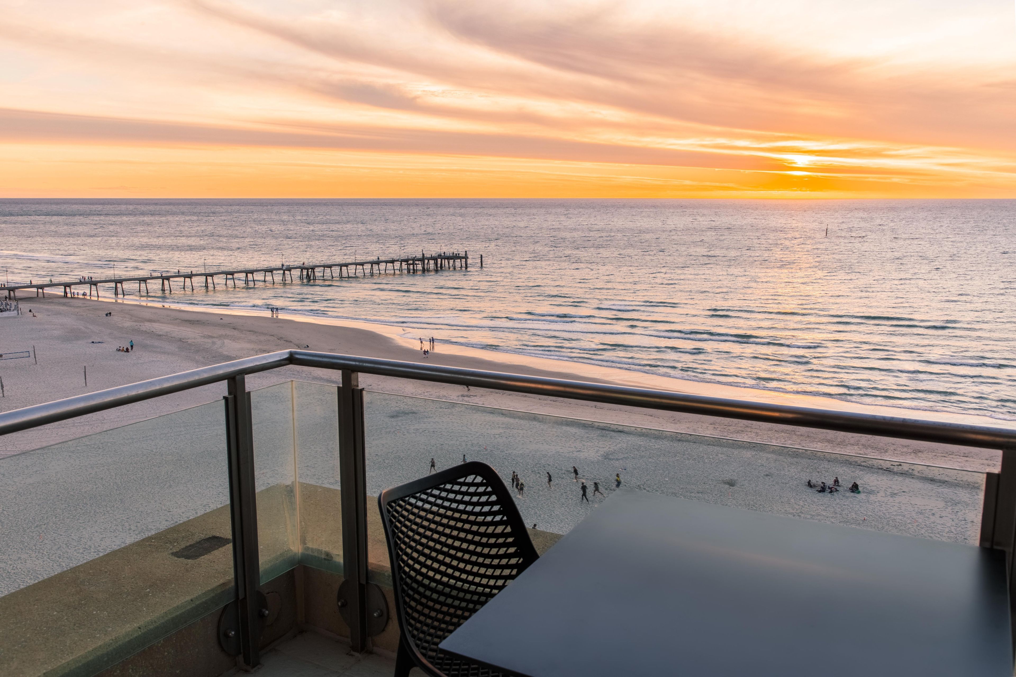 Varanda com vista para a praia e o cais ao pôr do sol.