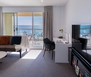 A modern hotel room with a balcony, a desk, a sofa, and a TV. - Oaks Glenelg Plaza Pier Suites (Glenelg)