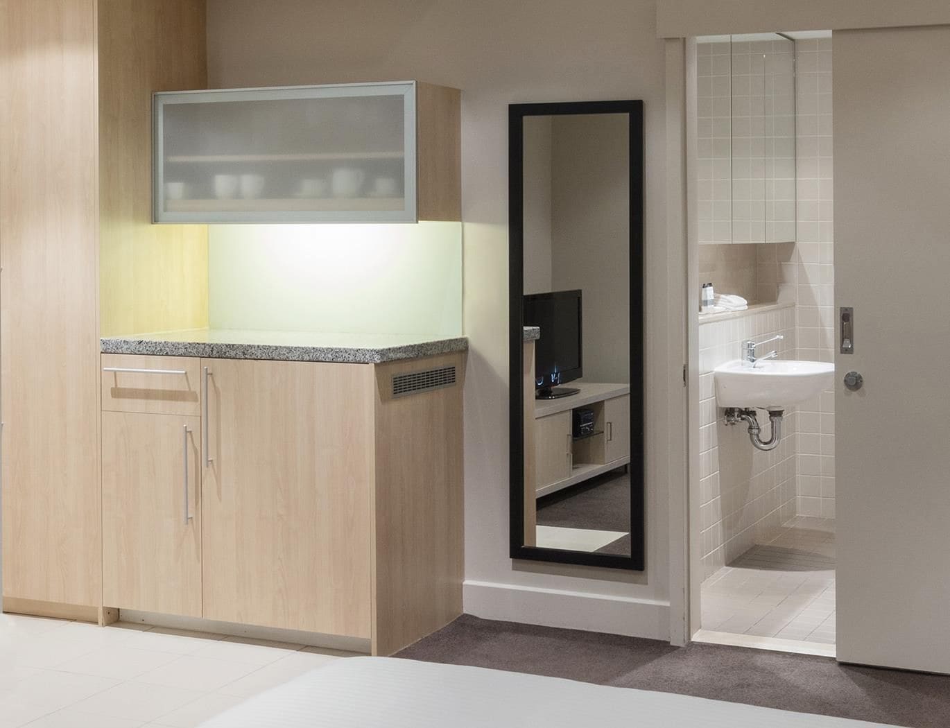 Et moderne badeværelse med vask, spejl og toilet.