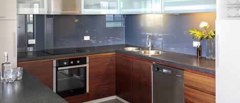 A modern kitchen with stainless steel appliances, wooden cabinets, and a granite countertop.