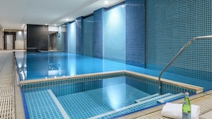 Une piscine aux carreaux bleus, une échelle en métal et une bouteille de bière posée sur le bord.