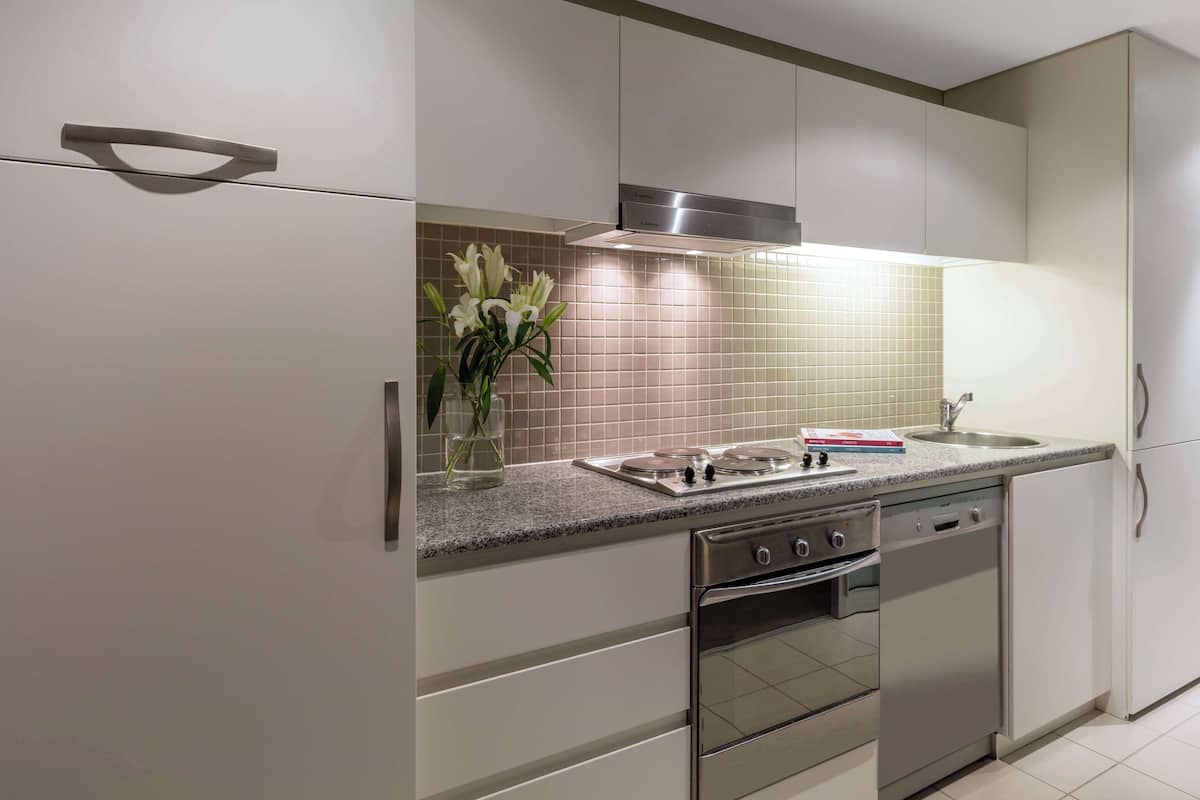 Een moderne keuken met roestvrijstalen apparatuur, een granieten aanrecht en een vaas witte bloemen.