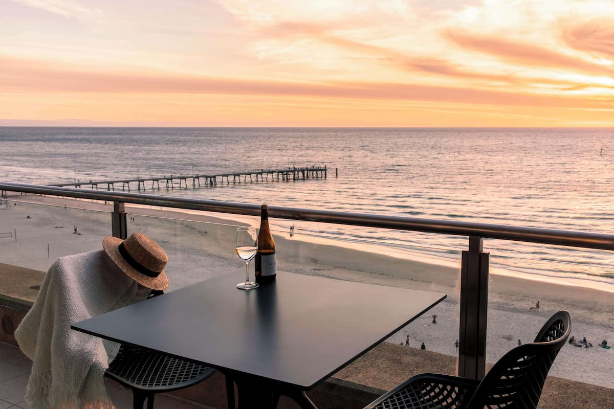 Een tafel met een fles en glas, met uitzicht op een strand en pier.