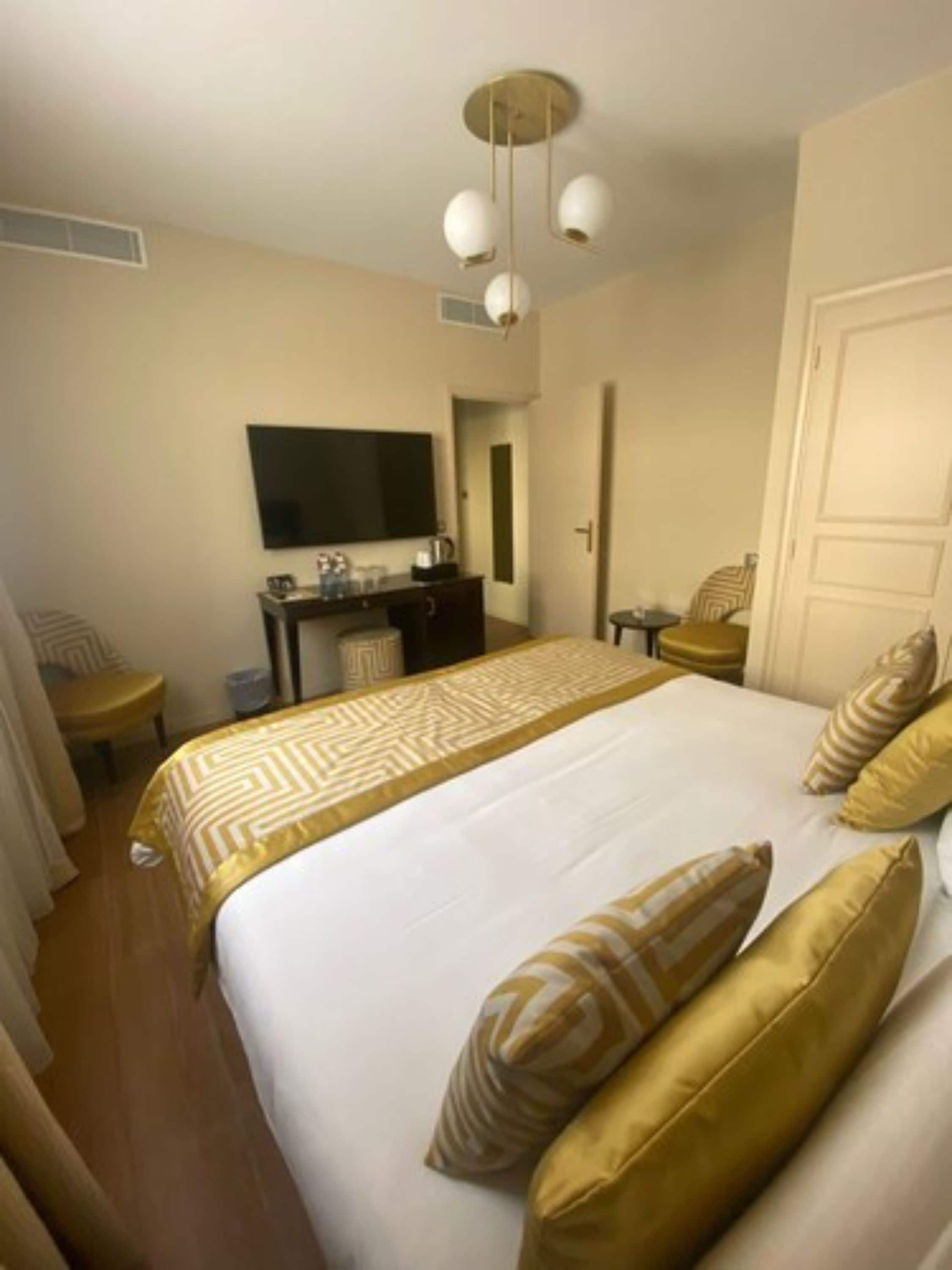 Habitación de hotel con una cama grande, un escritorio con televisor de pantalla plana, una silla y una mesita.