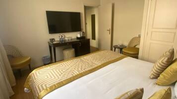 Habitación de hotel con una cama grande, un escritorio con televisor de pantalla plana, una silla y una mesita.