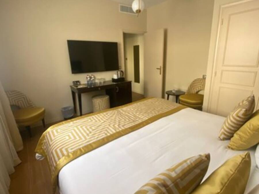 Habitación de hotel con una cama grande, un escritorio con televisor de pantalla plana, una silla y una mesita.
