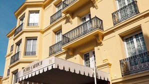 Ein mehrstöckiges Hotel mit Balkonen, einer roten Eingangstür und einem überdachten Eingangsbereich.