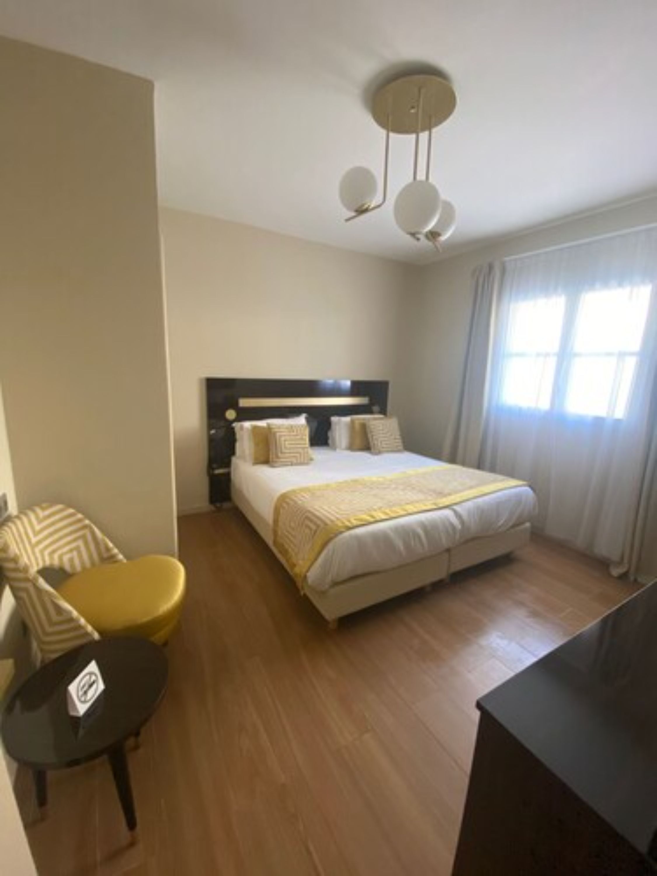 A hotel room with a bed, a chair, a small table, and a TV.