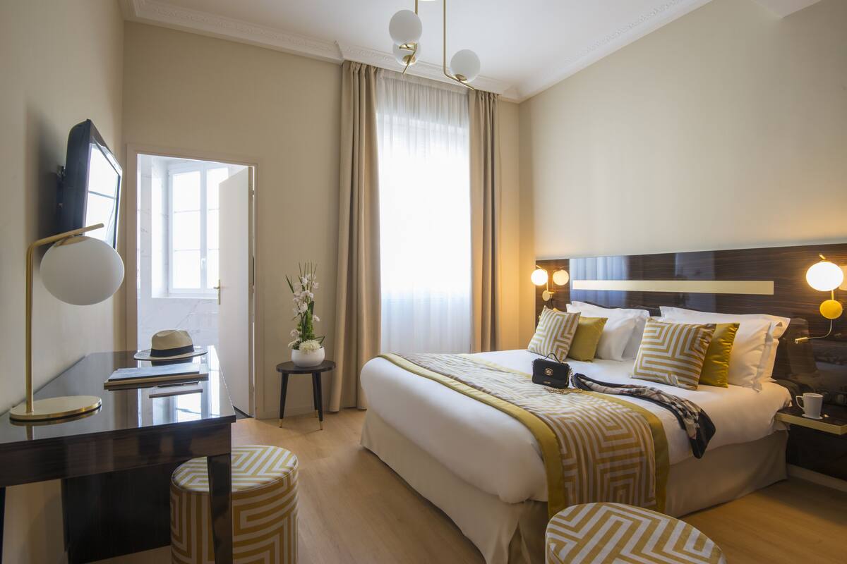 A hotel room with a large bed, bedside tables, a desk, and a chair.