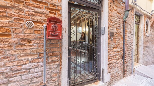 A stone building with a metal gate and a red mailbox. - Ca' Valeri (Venice)