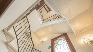 A staircase with a metal railing, a wooden door, and a wall-mounted light fixture. - Ca' Valeri (Venice)