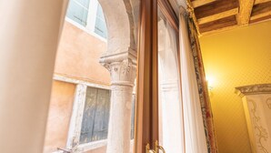 A doorway with a wooden frame and a brass doorknob, leading to a room with a patterned wallpaper and a yellow wall. - Ca' Valeri (Venice)
