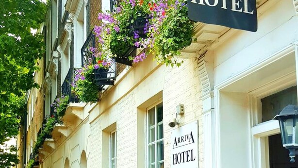 A traditional building with a sign reading "Arriva Hotel" and flower boxes on the windowsills. - Arriva Hotel (London)