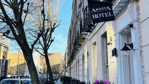 A row of traditional brick buildings with a sign for "Arriva Hotel" on the corner. - Arriva Hotel (London)