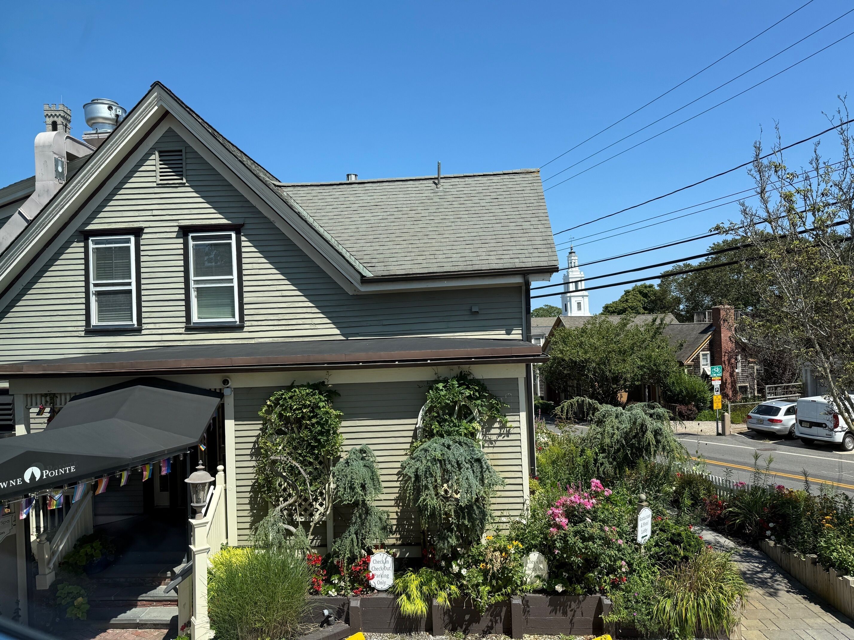 Un bâtiment à deux étages avec une façade verte, une entrée couverte portant l’enseigne « WNE Pointe Spa » et un panneau indiquant un espace de stationnement réservé aux clients effectuant leur enregistrement ou leur départ.
