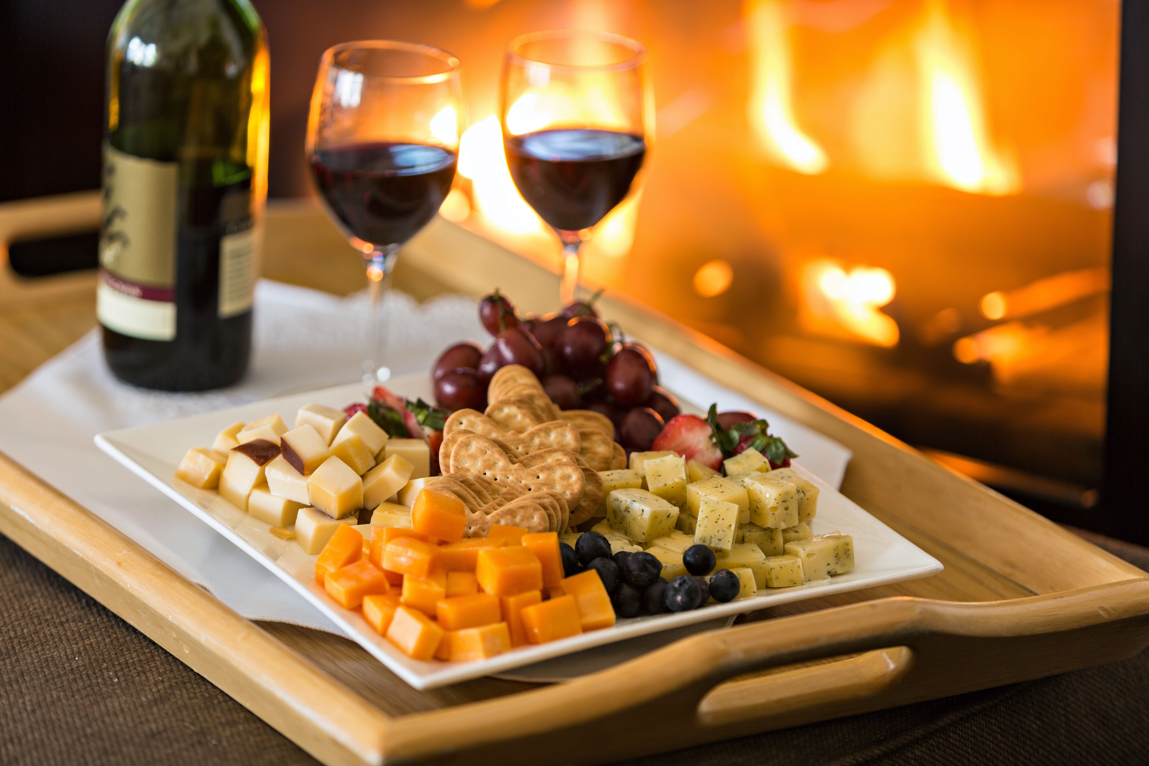 A cheese platter with crackers and grapes on a tray.