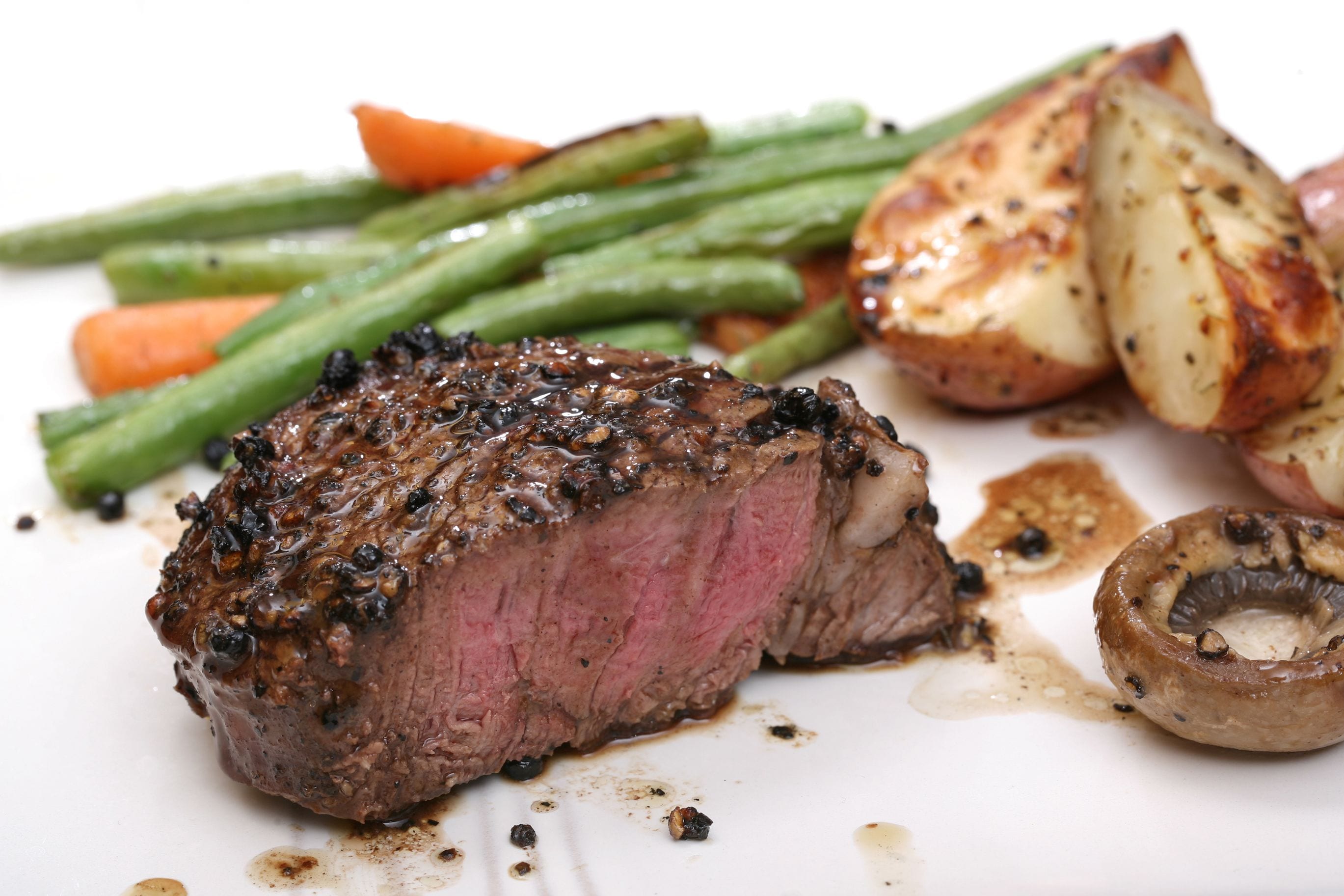 A steak with grilled vegetables and mushrooms on a plate.