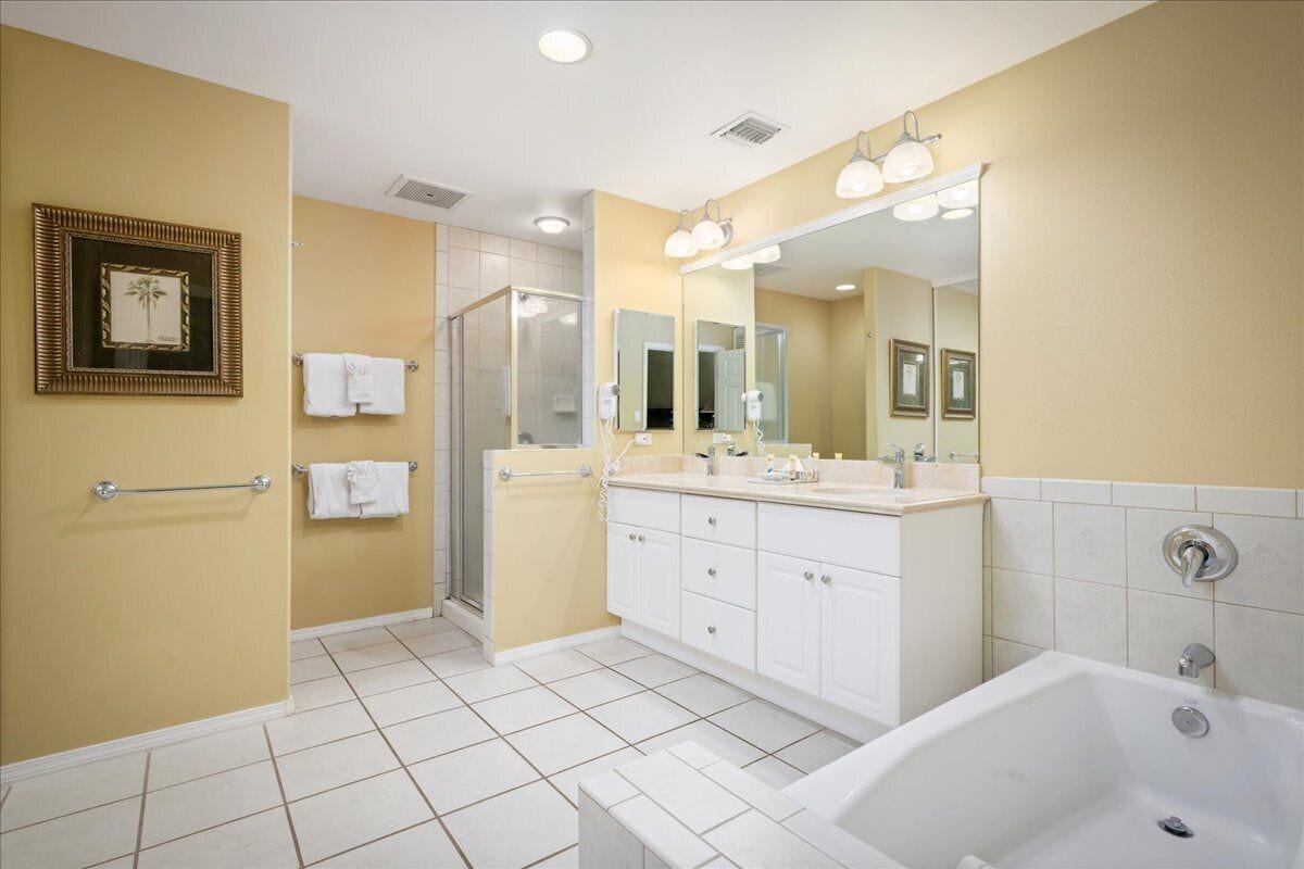 A modern bathroom with a large mirror, a bathtub, and a shower area.