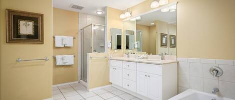 A modern bathroom with a large mirror, a bathtub, and a shower area.