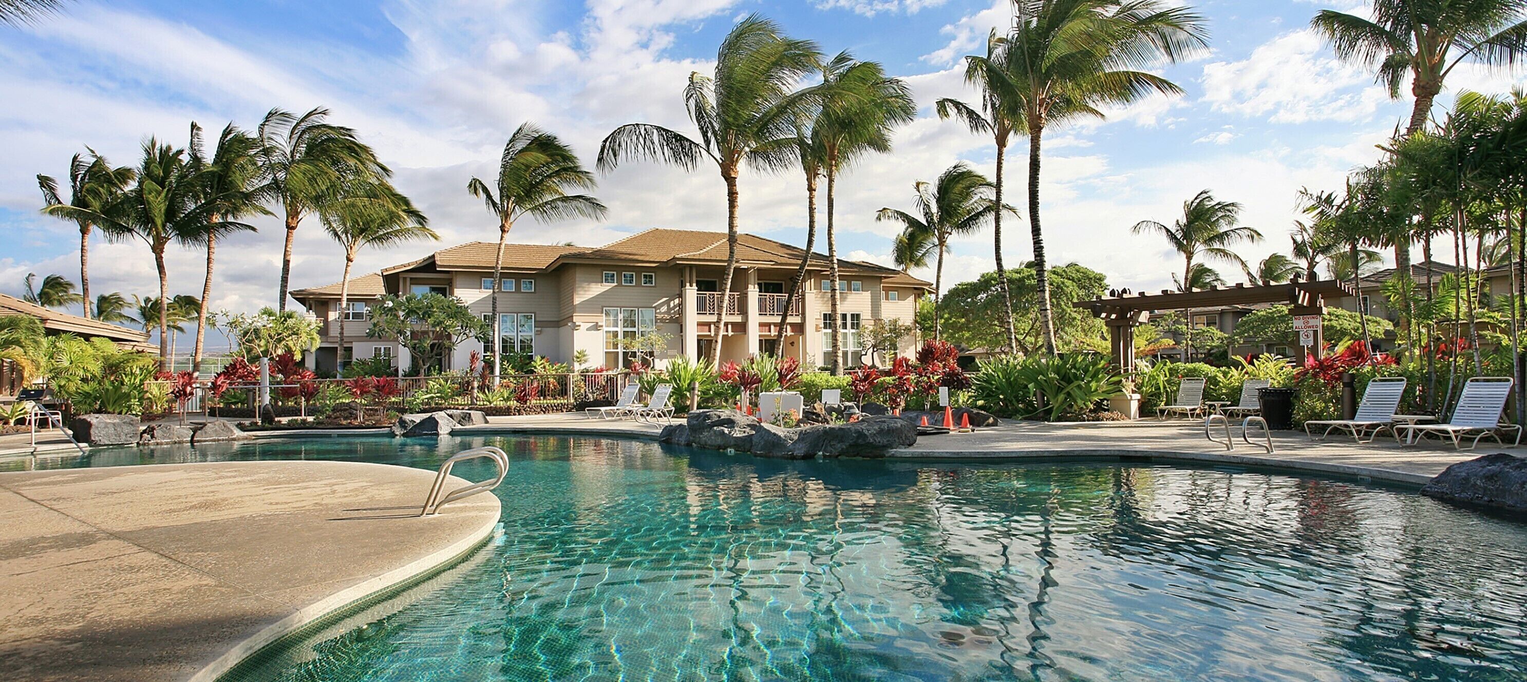 Ein Resort mit Schwimmbad, Palmen und einem Gebäude mit Balkonen.