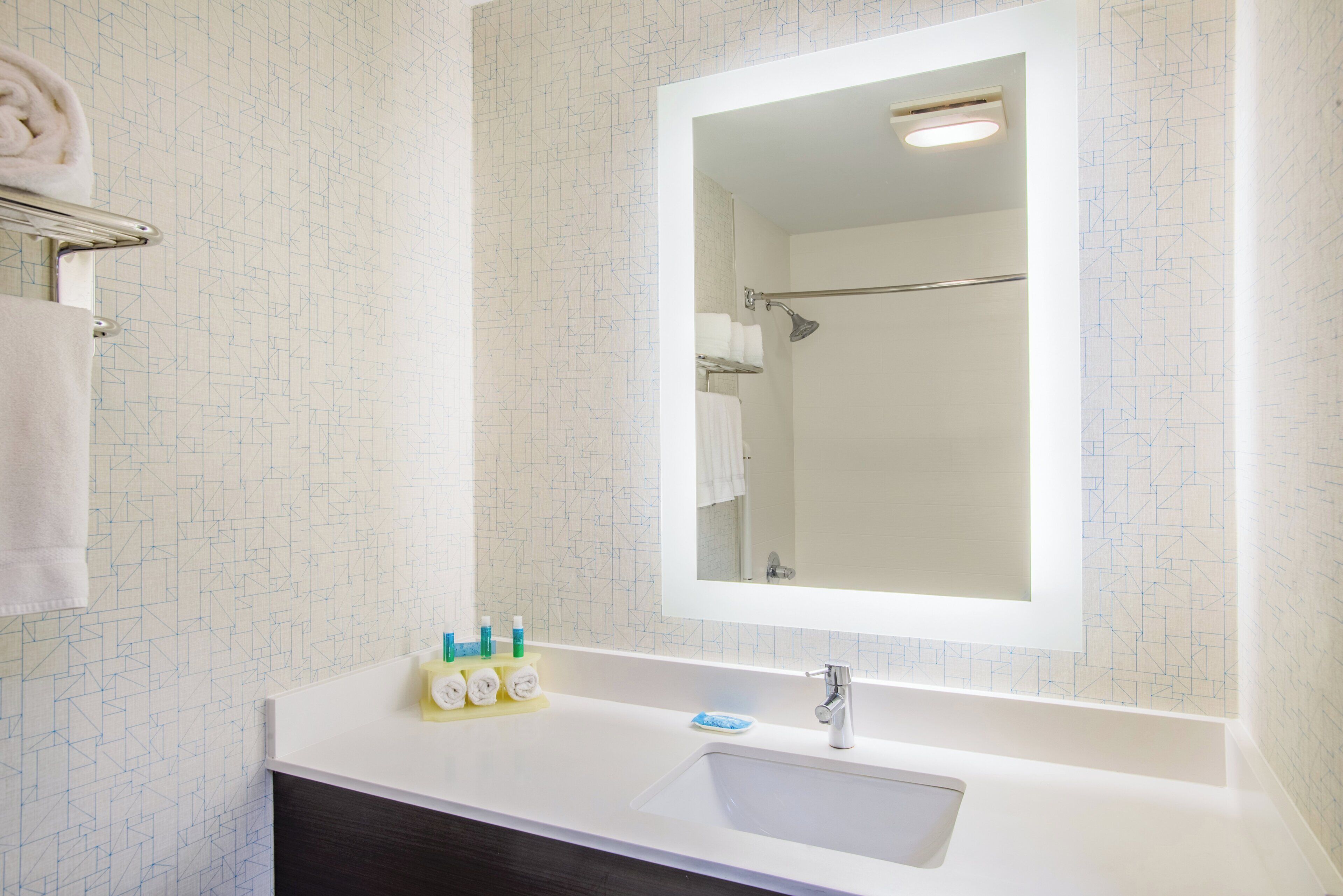 A bathroom with a white sink, a mirror, and a shower.