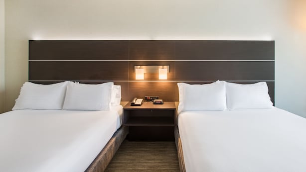 A hotel room with two beds, a nightstand with a phone and a clock, and a headboard with built-in lighting. - Holiday Inn Express Hotel & Suites Boston-Marlboro by IHG (Hudson)