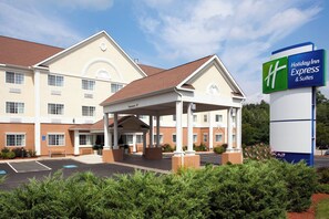 Un Holiday Inn Express & Suites con entrada cubierta, un estacionamiento y un cartel que indica una altura libre de 13 pies.