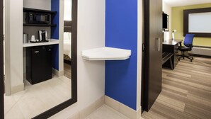 A hotel room with a kitchenette, a white shelf, a desk with a chair, and a large window. - Holiday Inn Express Hotel & Suites Boston-Marlboro by IHG (Hudson)