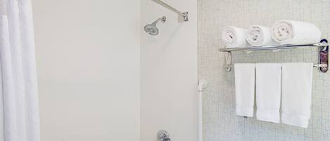 A shower with a handheld showerhead, a glass door, and a towel rack with three towels.