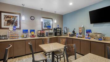 A hotel breakfast area with a counter, seating, and various food and beverage stations.