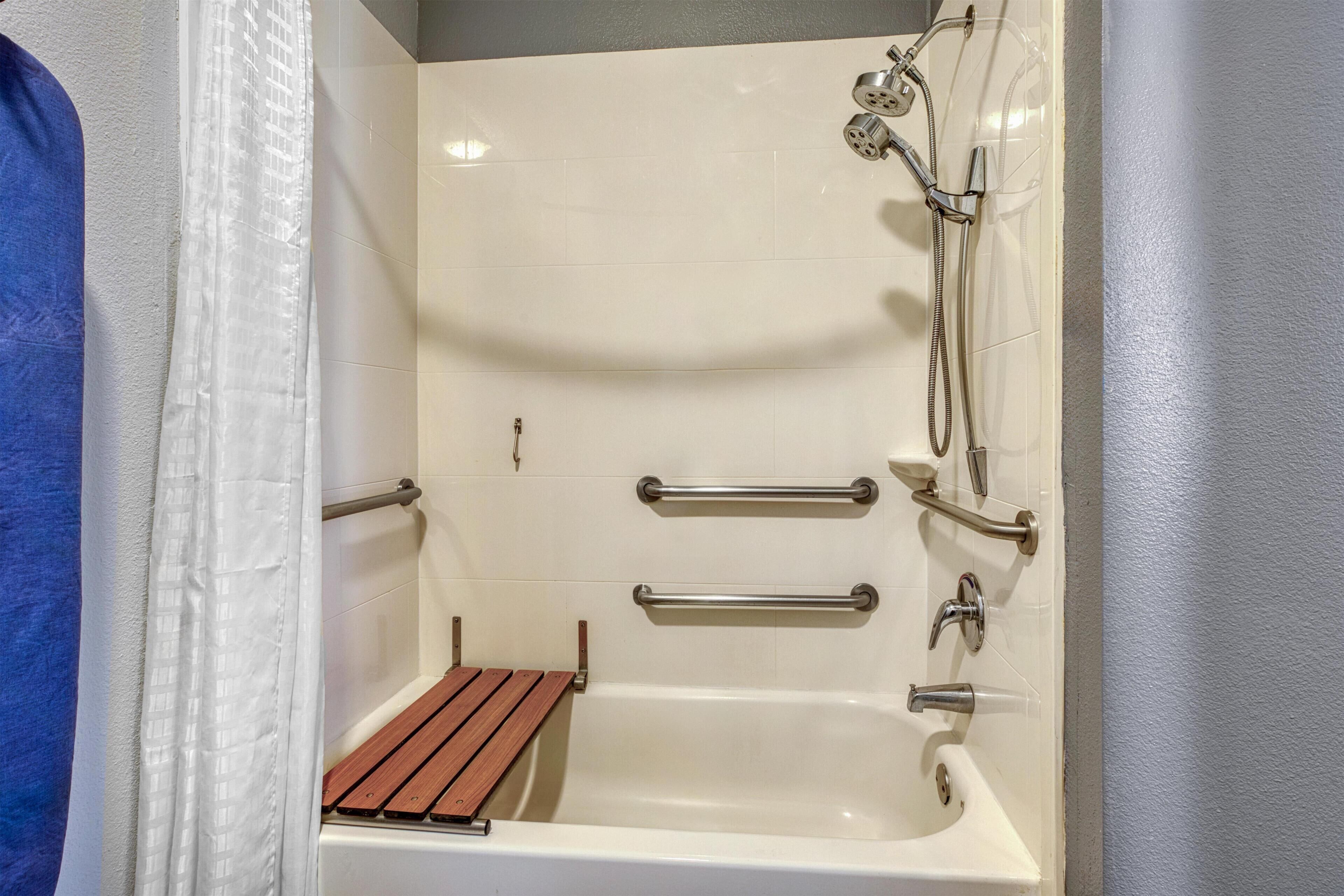 Ein Badezimmer mit einer Badewanne, einer Dusche und Haltegriffen.