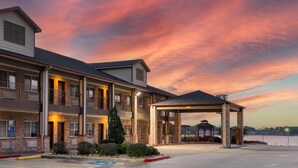 A multi-story hotel with a covered entrance and a view of a body of water. - Best Western Lake Conroe Inn (Montgomery)