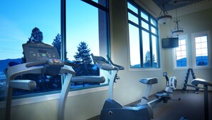 A gym with exercise equipment, large windows, and a TV. - Ramada Limited Merritt (Merritt)
