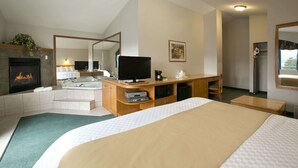 A hotel room with a large bed, a TV, a fireplace, a bathroom, and a desk. - Ramada Limited Merritt (Merritt)