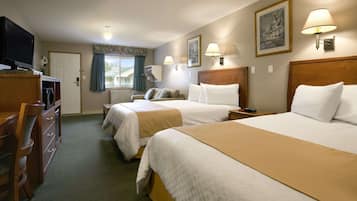 Habitación de hotel con dos camas, televisión, escritorio y ventana con cortinas.