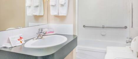 Un baño con lavamanos, espejo y zona de ducha.