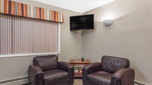 Una habitación con dos sillones de cuero, un televisor de pantalla plana montado en la pared y una cortina a rayas.