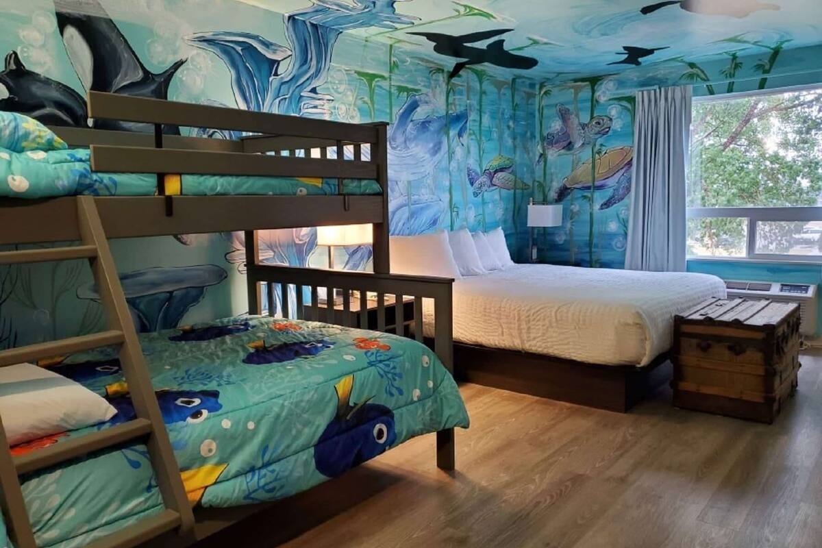 Habitación infantil con literas, una cama y una ventana con cortinas.