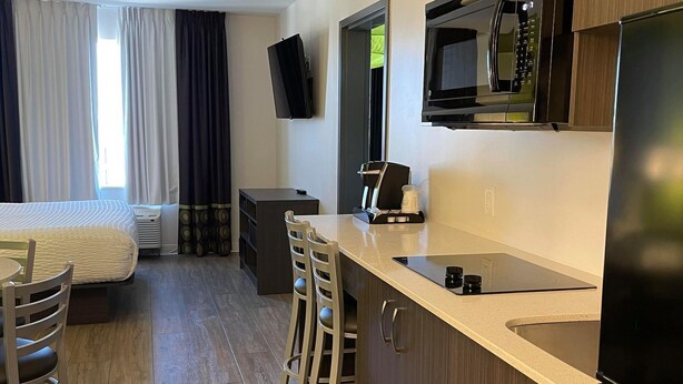 A compact hotel room with a kitchenette, a bed, a TV, and a seating area. - Super 8 by Wyndham Winnipeg East MB (Winnipeg)