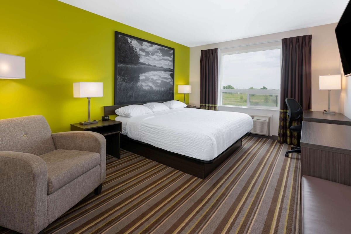 Habitación de hotel con una cama grande, un sofá, un escritorio y una ventana con cortinas.