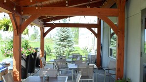 An outdoor patio with wooden beams, tables, and chairs. - Super 8 by Wyndham Winnipeg East MB (Winnipeg)