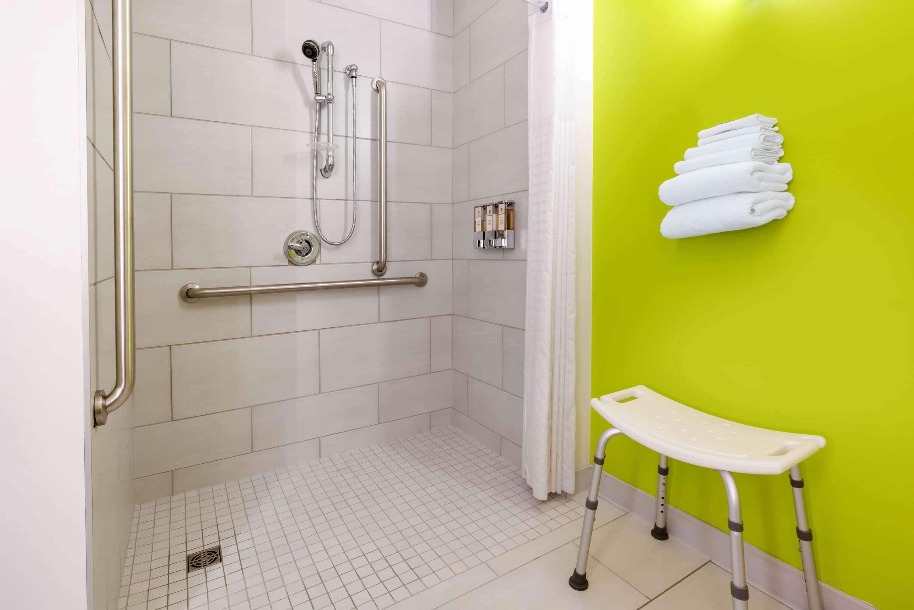 A shower area with grab bars, a wheelchair-accessible bench, and a towel rack.