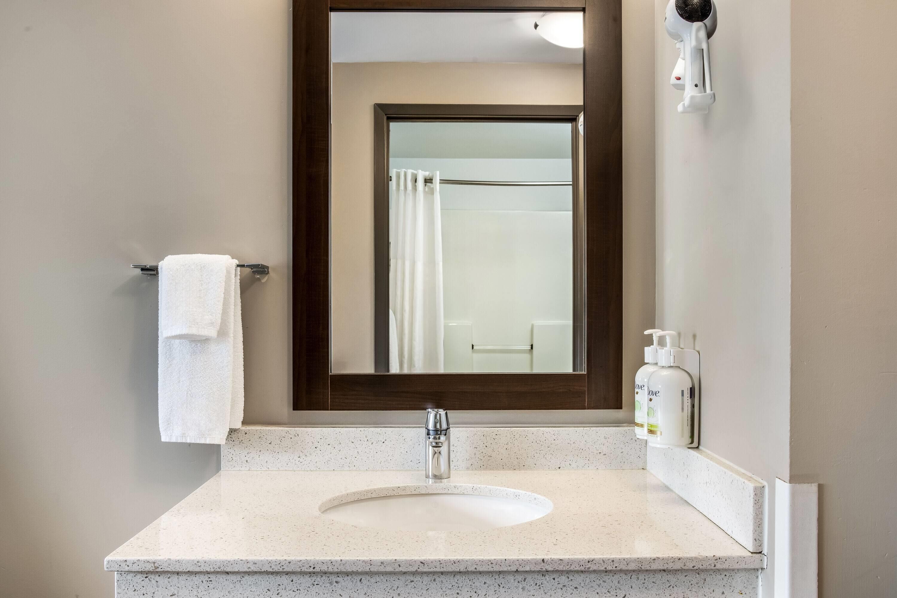 A bathroom with a white sink, a towel rack, a mirror, and a shower curtain.