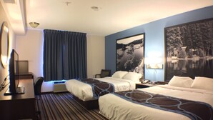 A hotel room with two beds, a desk, a chair, a lamp, and a large framed picture on the wall.