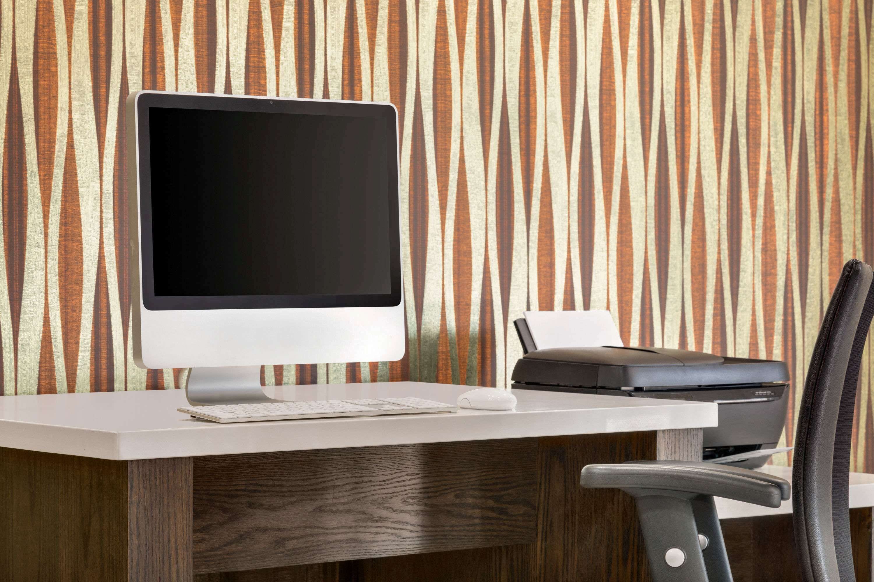Un escritorio moderno con una computadora de escritorio, una impresora y una silla.
