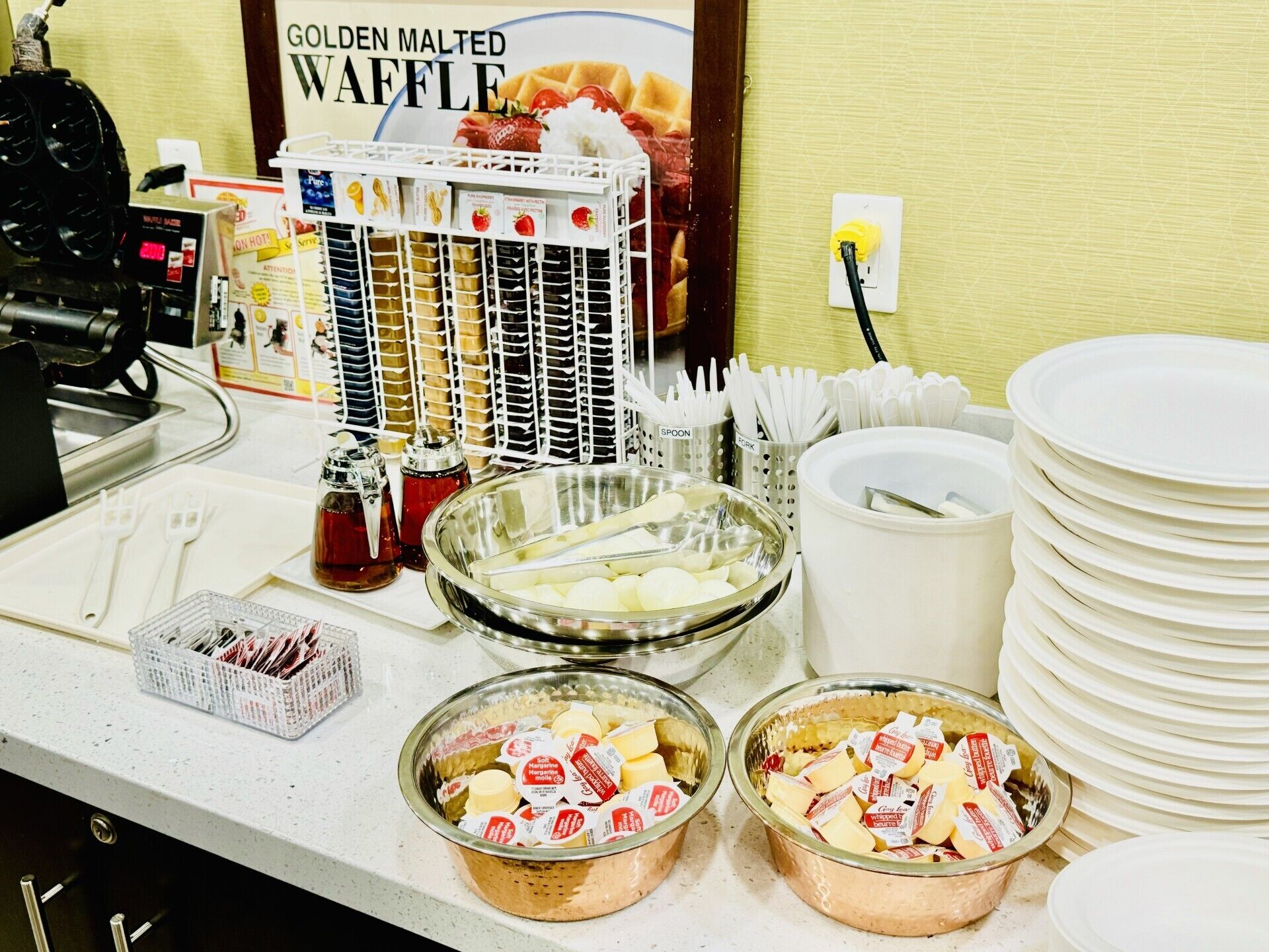 Montaje de buffet con diferentes opciones de comida, incluyendo tazones de queso y una presentación de waffles.